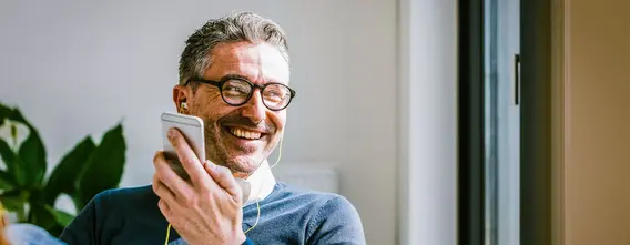 Large_web_and_screen-a_happy_man_wearing_earphones_listens_to_something_from_his_mobile_phone